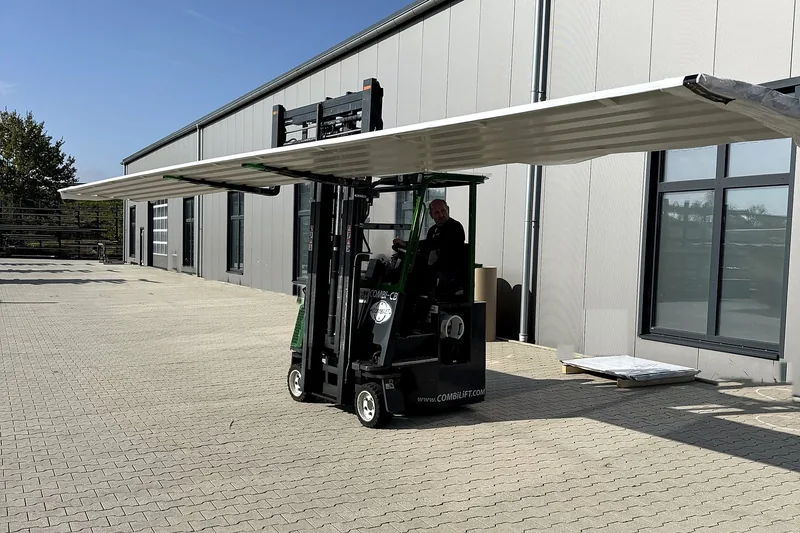 Lange Trapezblechtafel am Stück wird mit dem Stapler über den Hof vor der Produktionshalle gefahren
